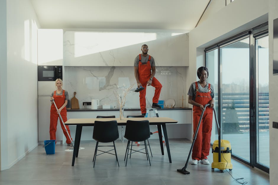Three cleaning staff working in a contemporary kitchen setting, showing teamwork and efficiency.