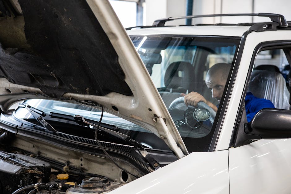 A mechanic performs a detailed inspection on a vehicle in a workshop setting.