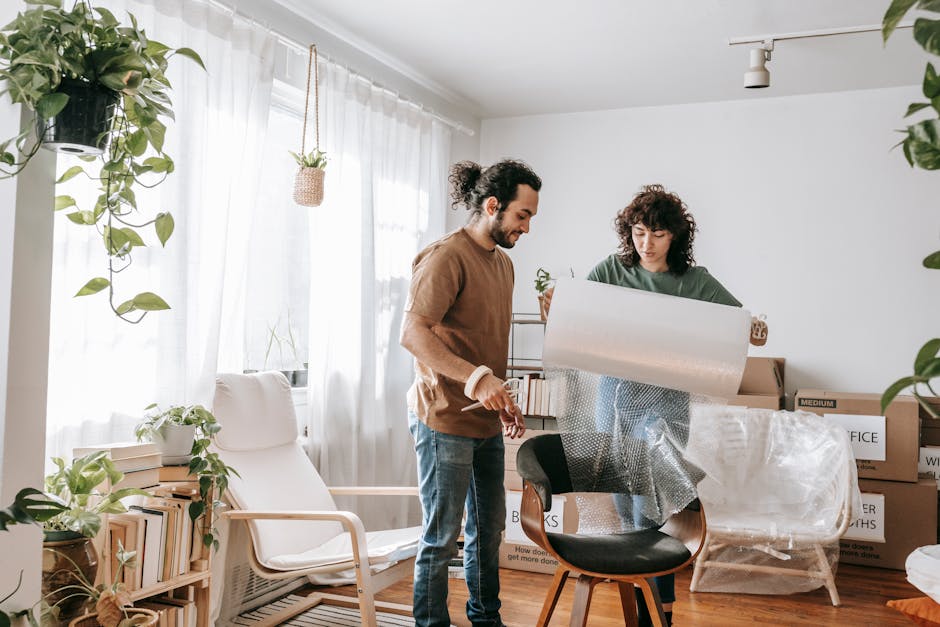 A joyful couple packing boxes and bubble wrap in a bright, indoor setting.