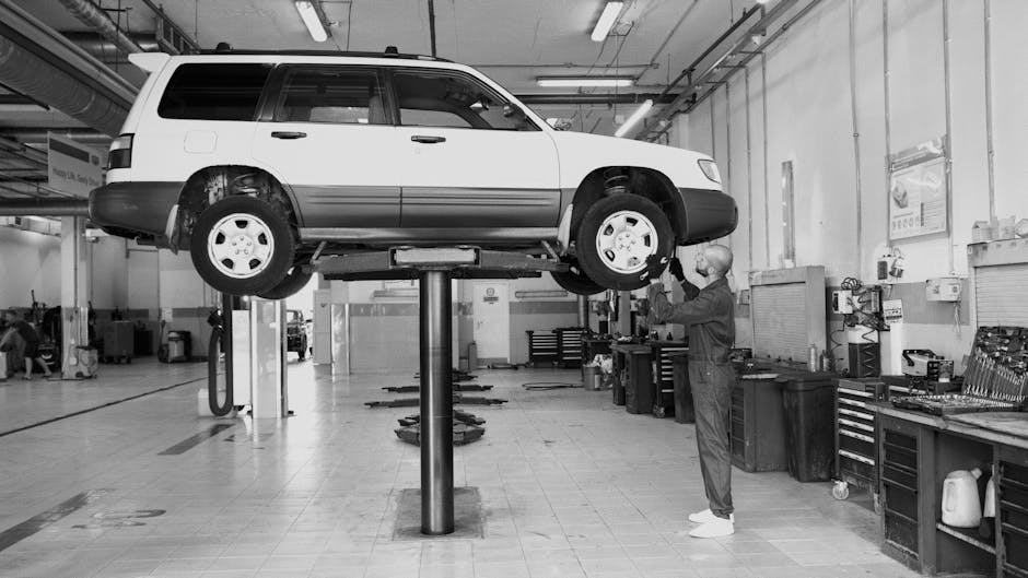 A mechanic examines an elevated car in a well-equipped auto repair shop.